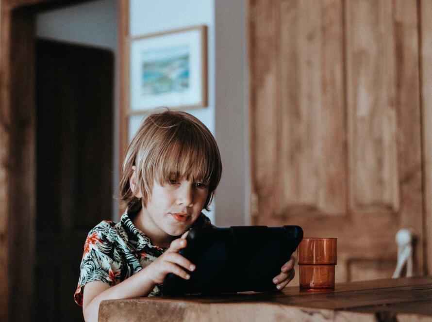 A young boy using a tablet computer in a kitchen.