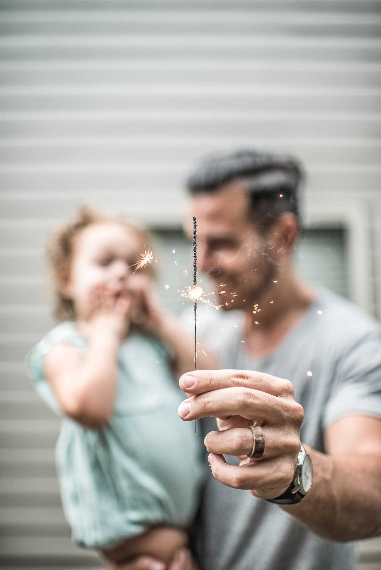 A man holding a sparkler with his daughter.