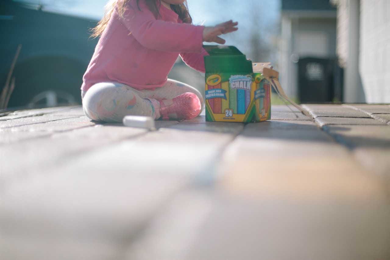 A little girl playing with a toy on the ground.