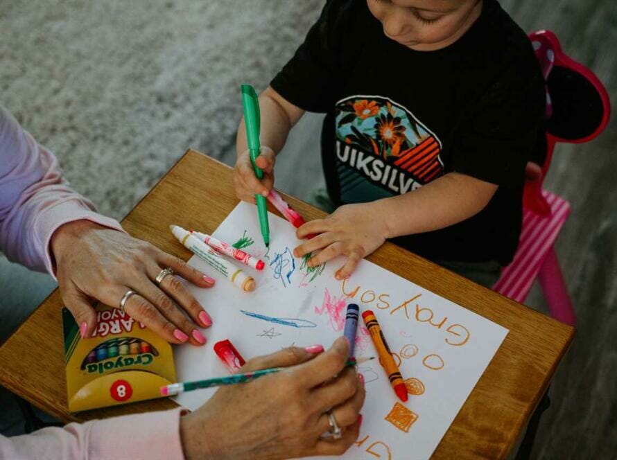 A woman and a child are drawing on a piece of paper.