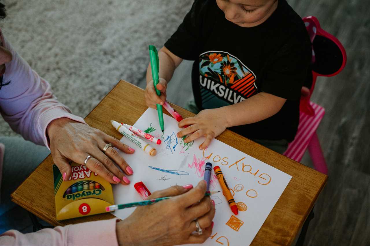 A woman and a child are drawing on a piece of paper.