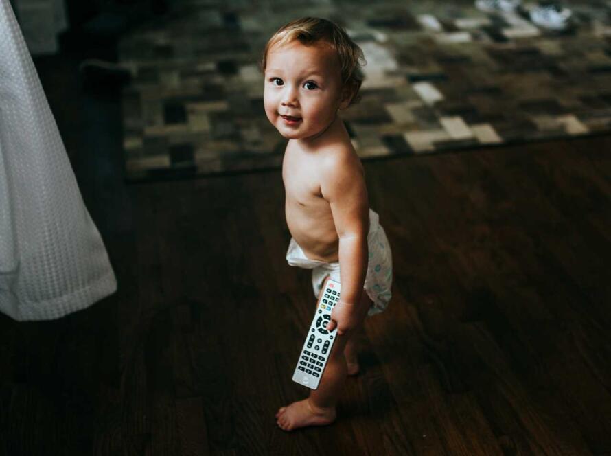 A baby holding a remote control in a living room.