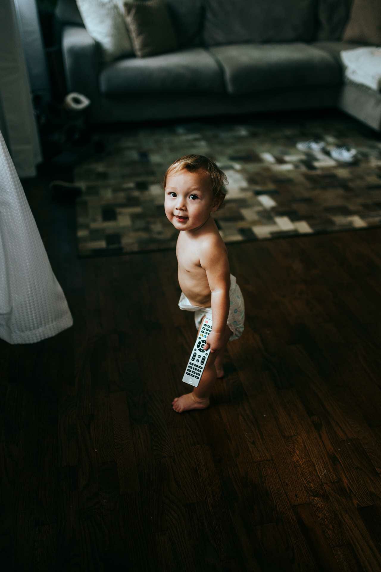 A baby holding a remote control in a living room.