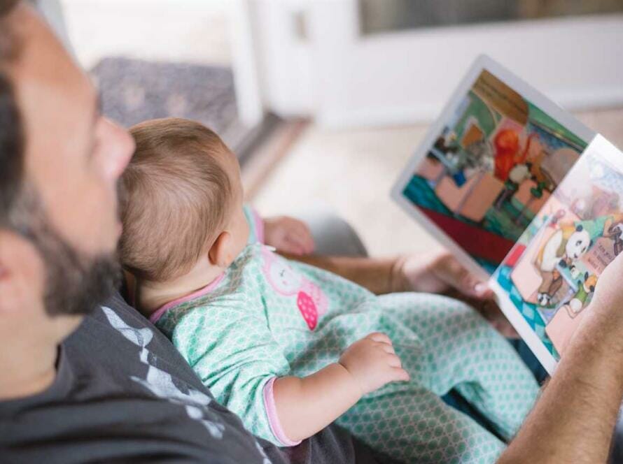 A man reading a book to his baby.