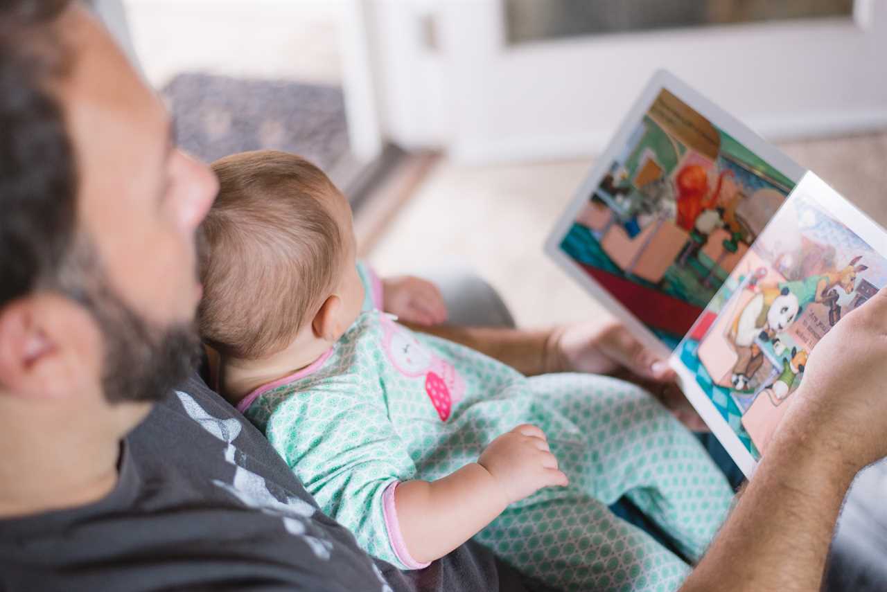 A man reading a book to his baby.