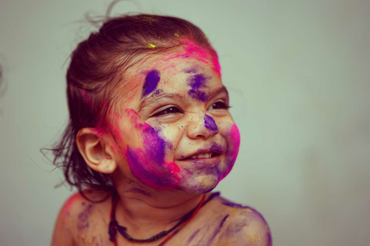 A little girl with colorful paint on her face.