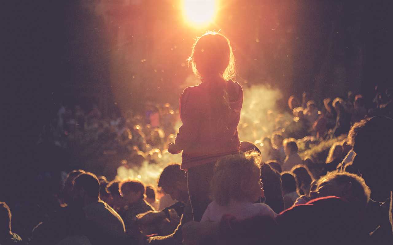 A crowd of people watching the sun go down at a concert.