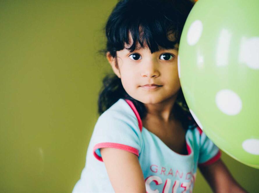 A little girl holding a green balloon.