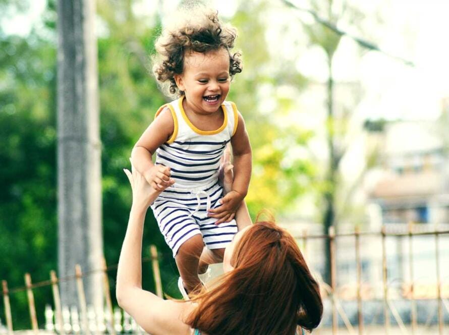 A woman is holding a child up in the air.