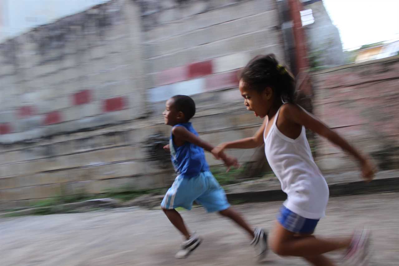 Two children running down a street.