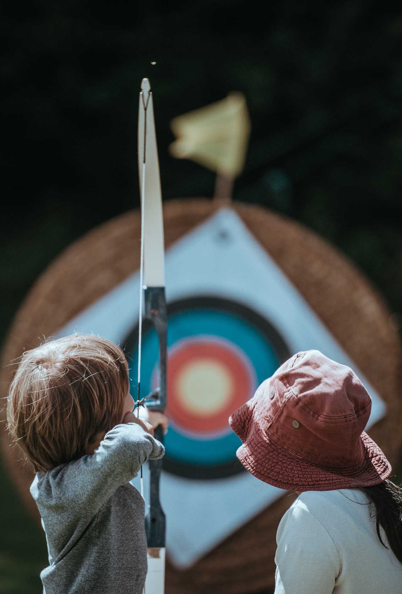 Two children aiming at an archery target.