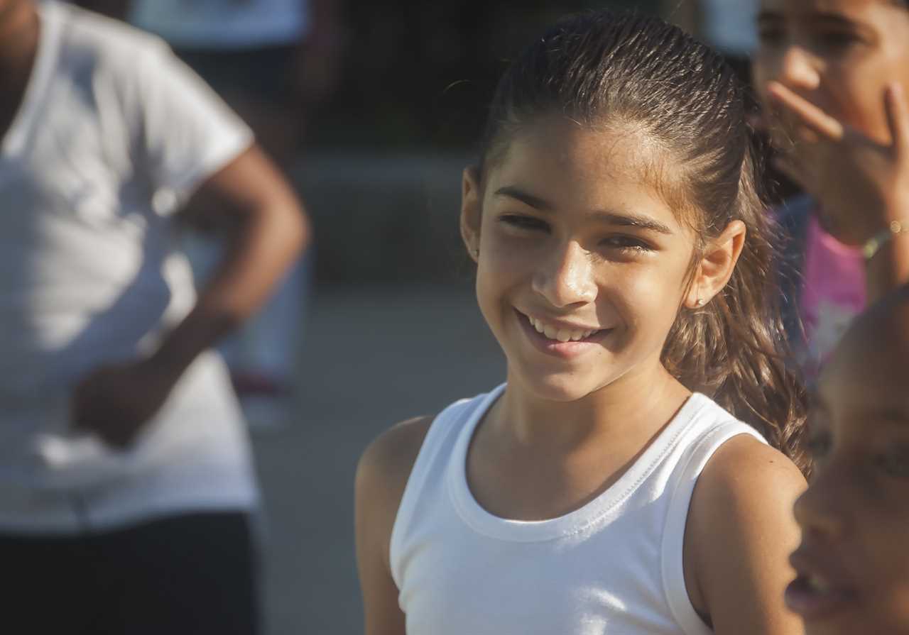 A young girl smiles in front of a group of people.