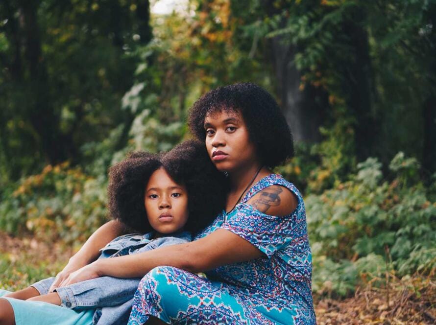 A mother and daughter sitting in the woods.