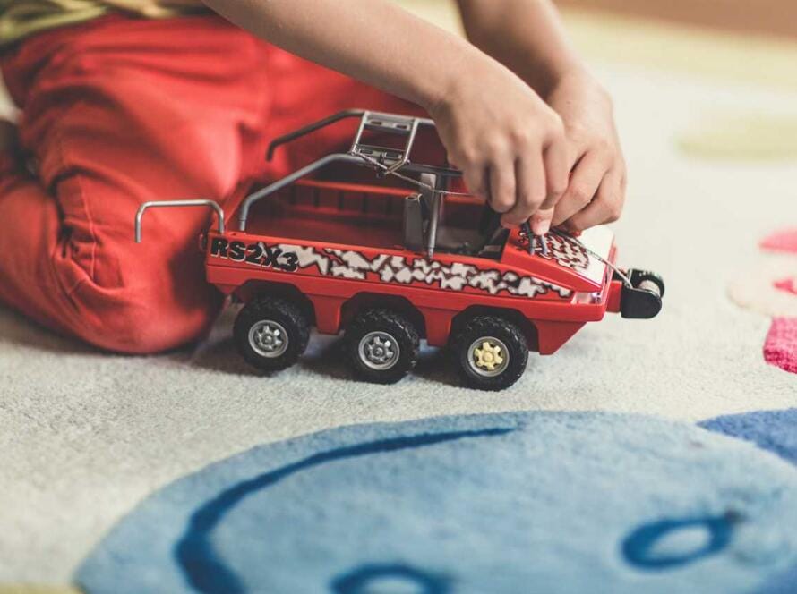 A child playing with a toy truck on the floor.