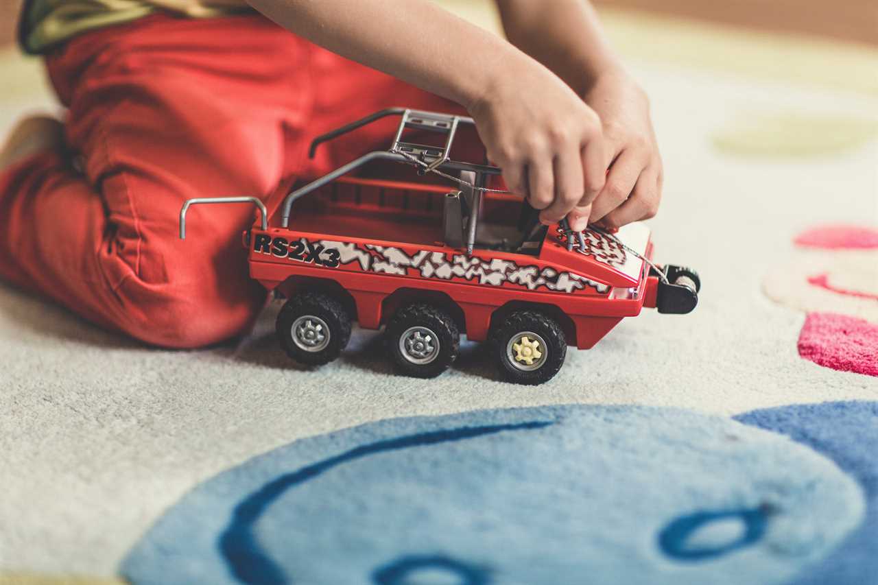 A child playing with a toy truck on the floor.