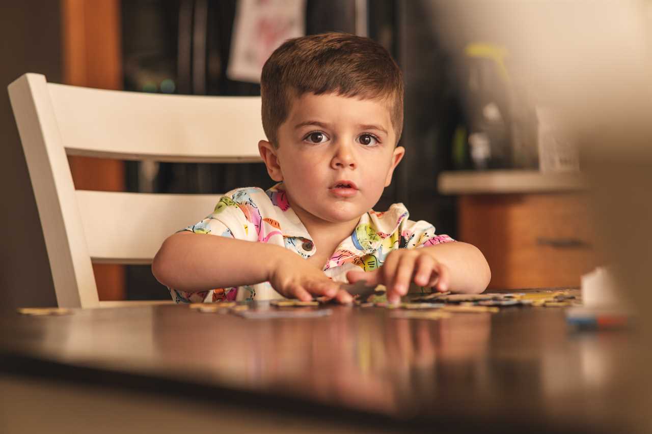 A young boy sitting at a table playing with puzzles.