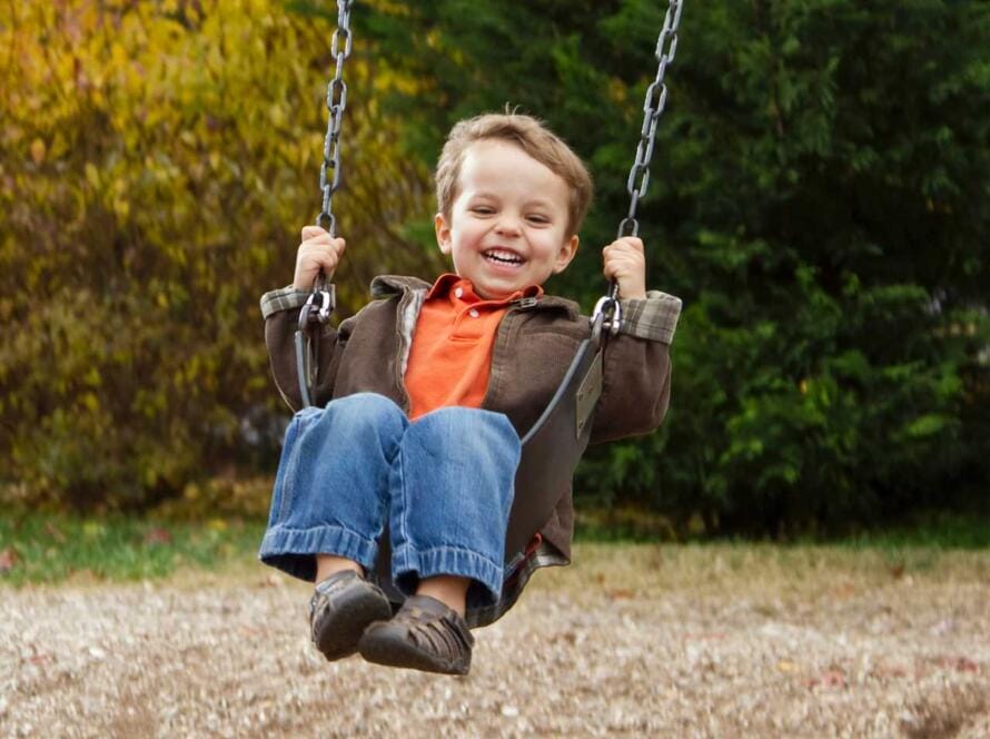 A young boy swinging on a swing.