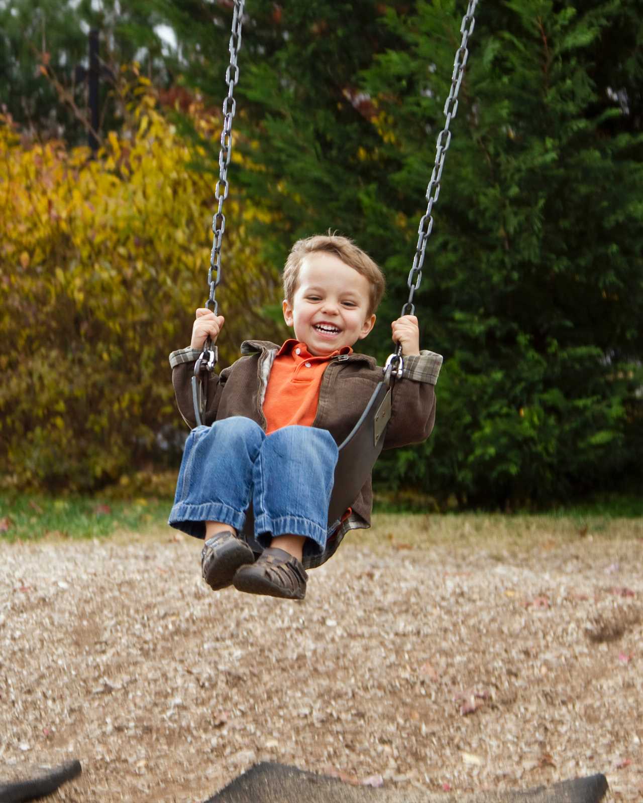 A young boy swinging on a swing.