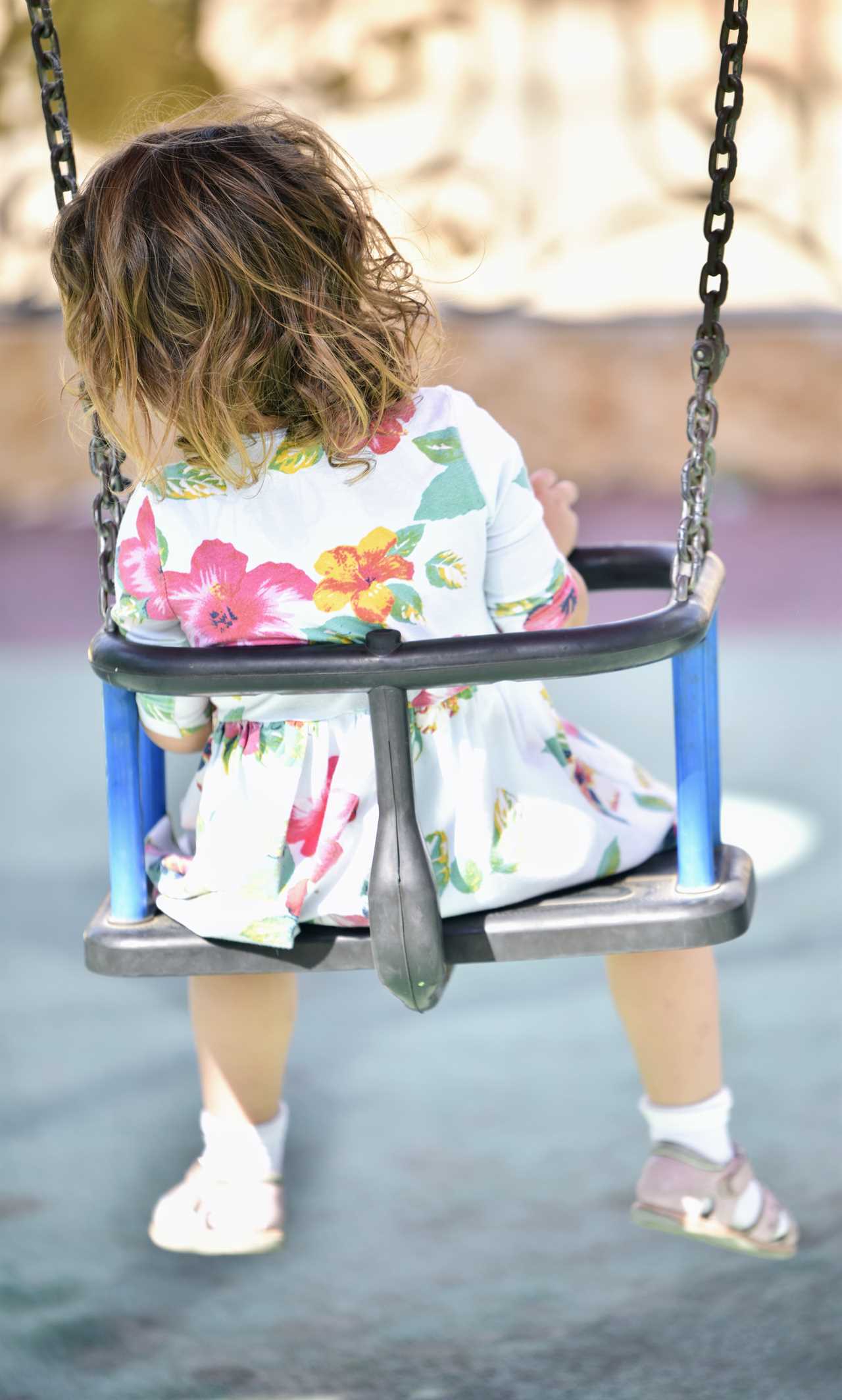 A little girl sitting on a swing.