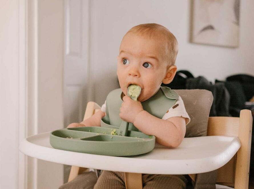 A baby is sitting in a high chair eating a food.