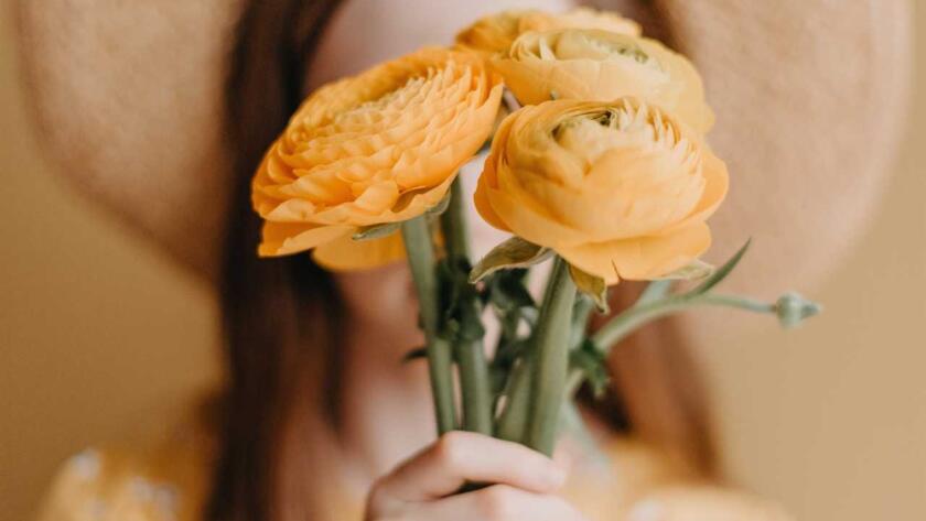 A girl in a straw hat holding yellow flowers.