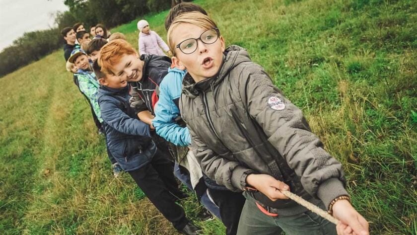 A group of children pulling a rope in a field.