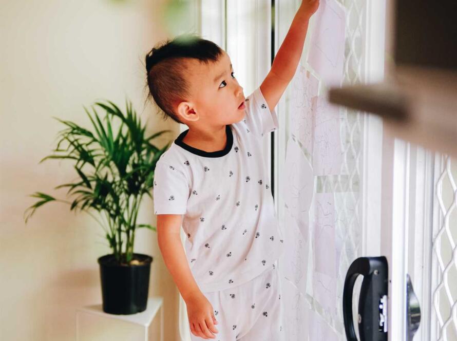 A young boy in pajamas standing near a door.