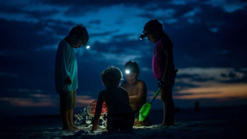 A group of people playing in the sand at night.