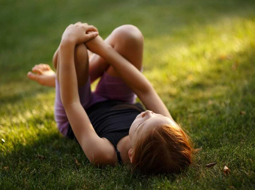 A little girl laying down in the grass.