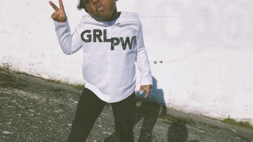 A little girl wearing a sweatshirt with the word grpw on it.