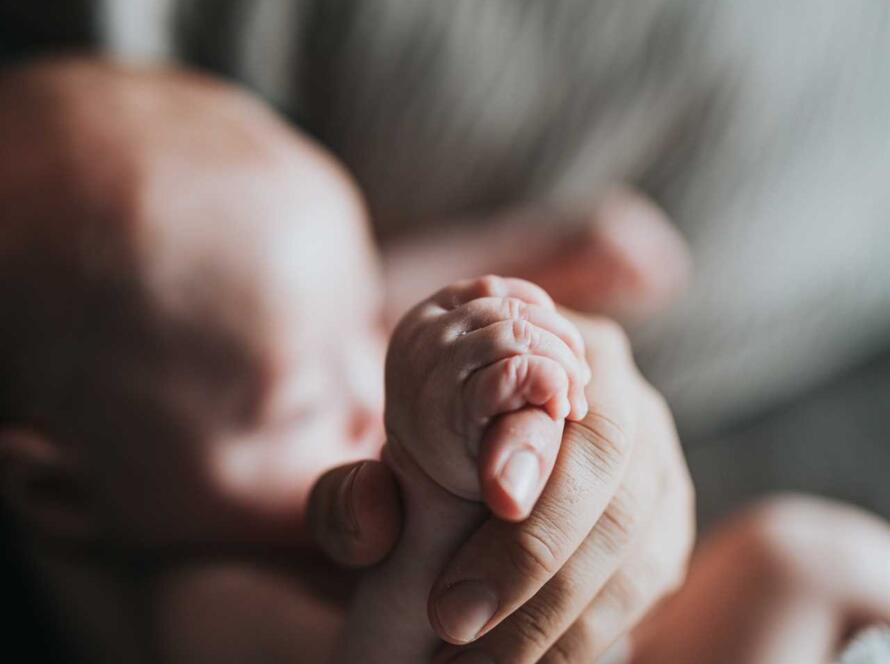 A close up of a baby's hand holding a blanket.