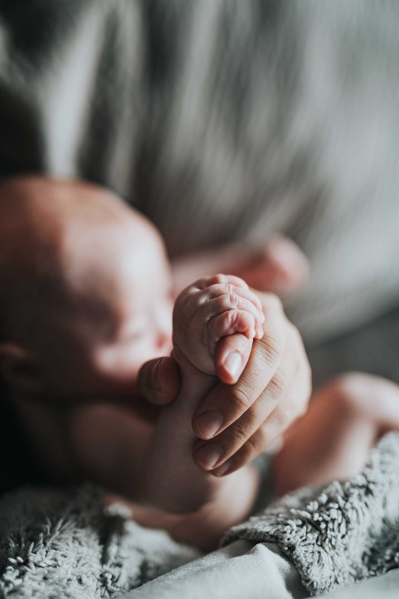 A close up of a baby's hand holding a blanket.