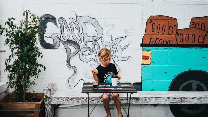 A boy sitting at a table with graffiti on the wall.