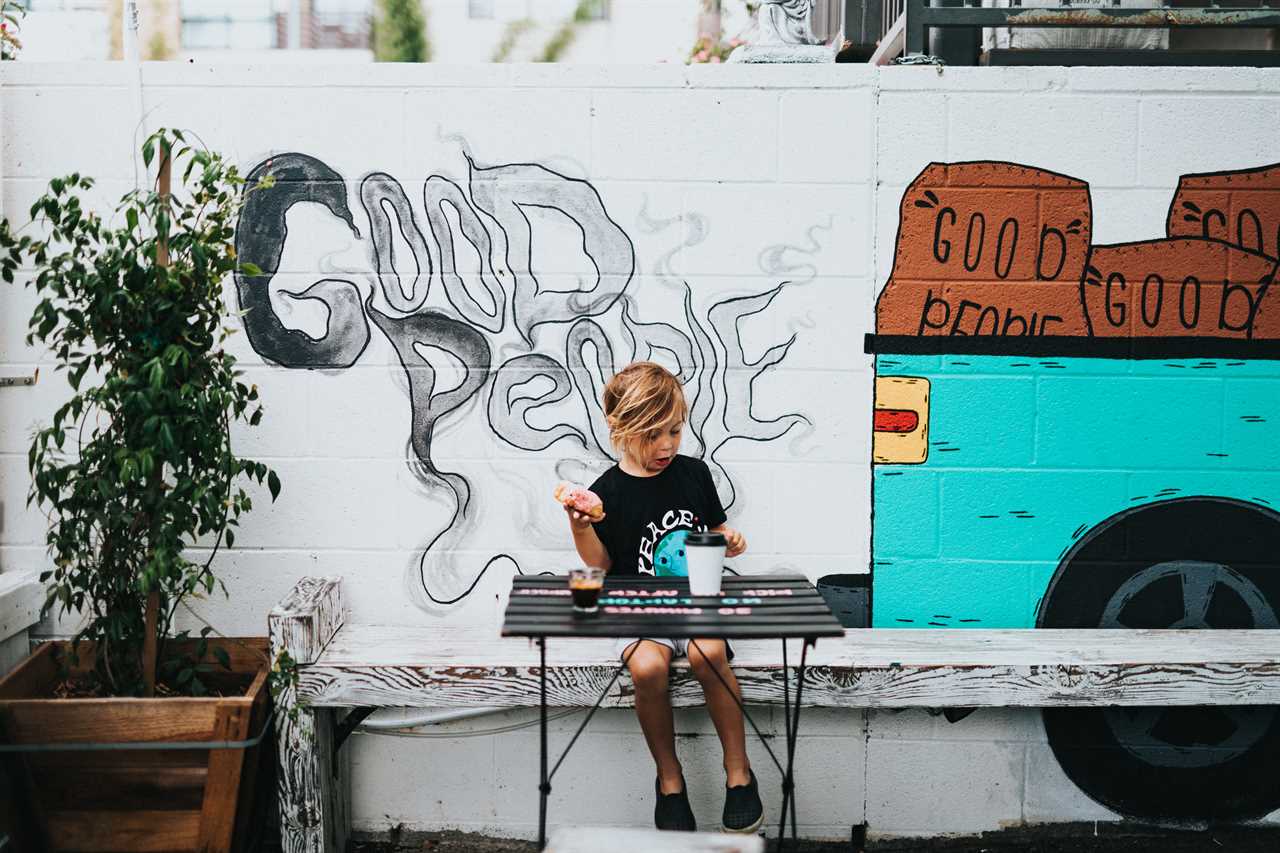 A boy sitting at a table with graffiti on the wall.