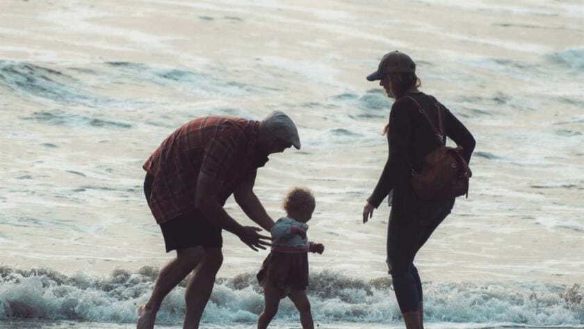 A family walking on a beach with a small child.