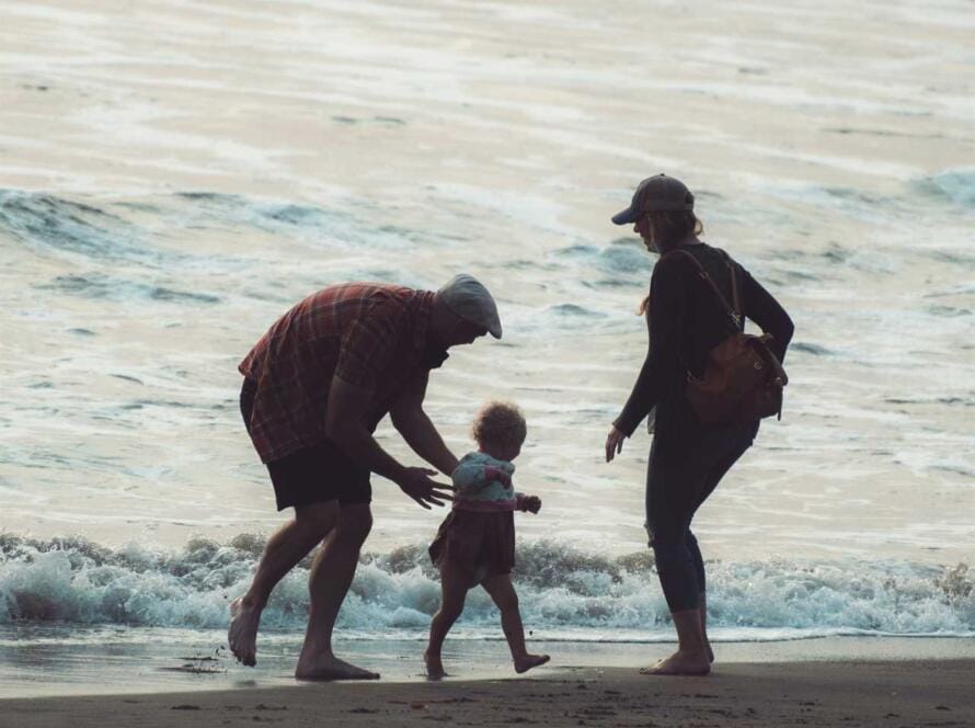 A family walking on a beach with a small child.