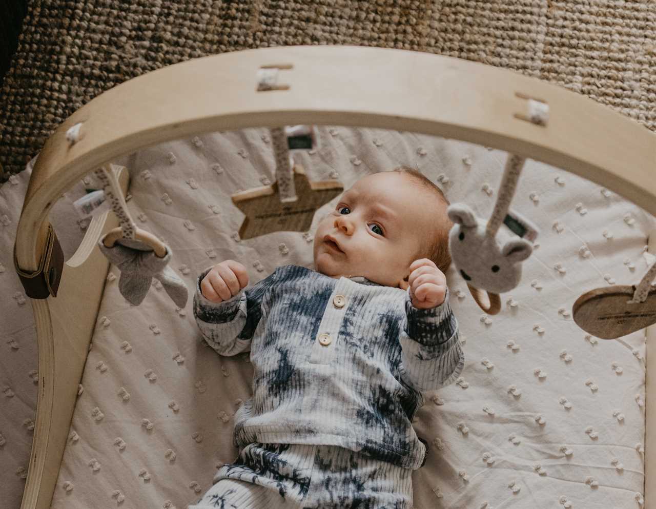 A baby is laying on a wooden cradle.