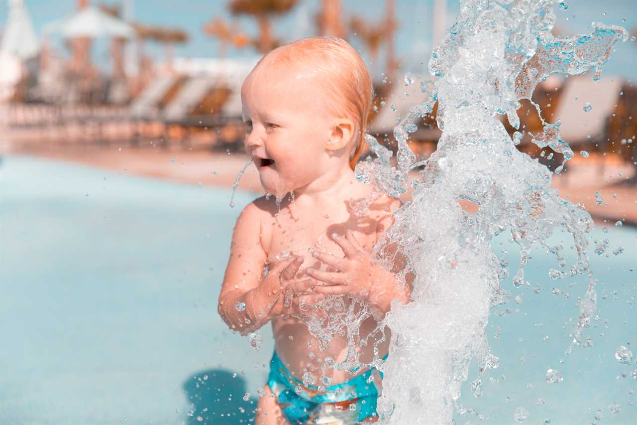 A toddler playing with water in a pool.