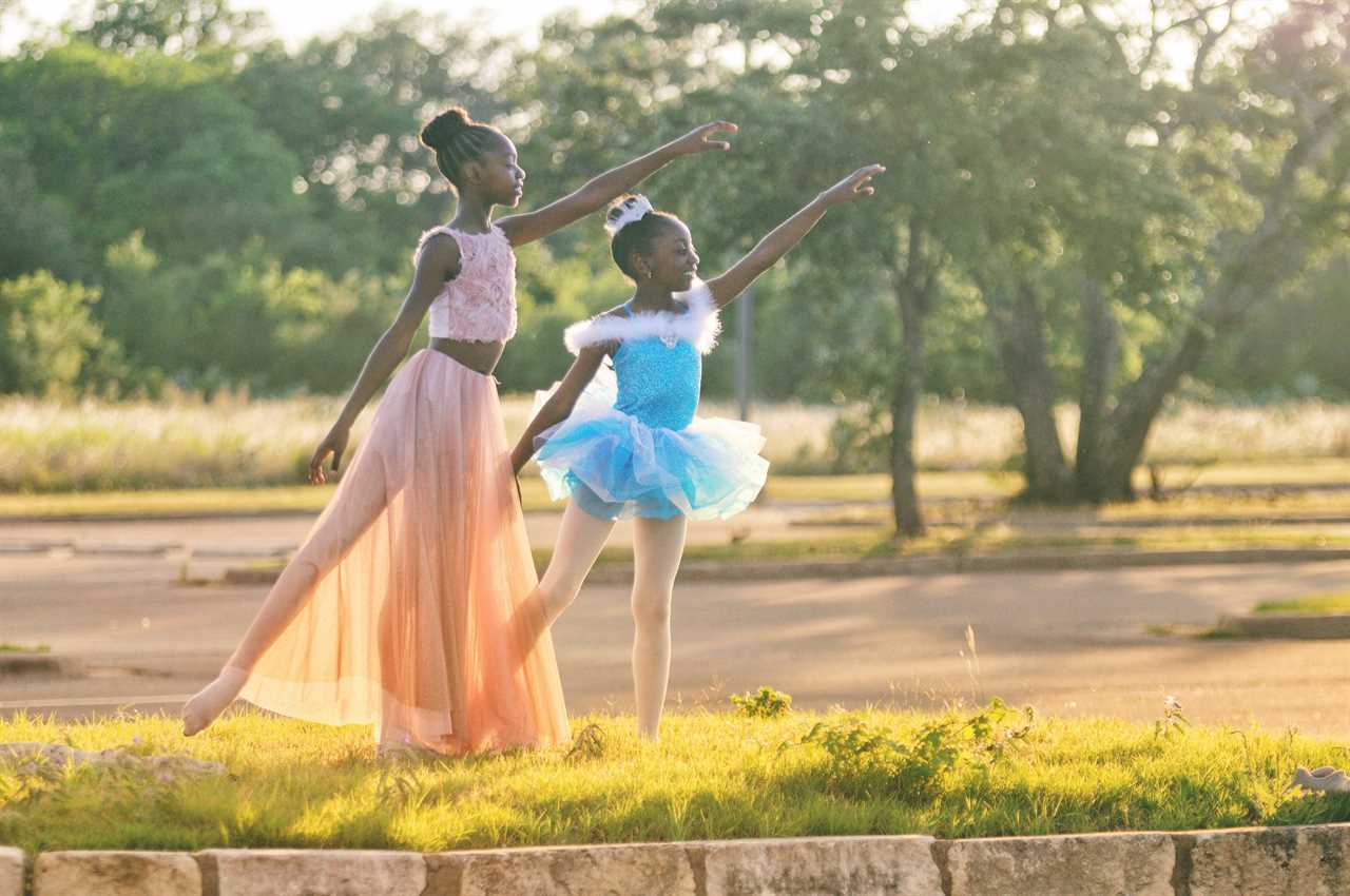 A mother and daughter dance in a park.