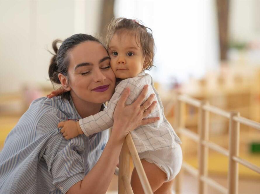 A woman is hugging a baby in a playroom.