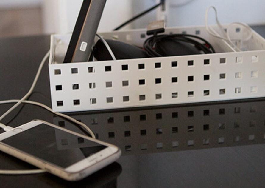 A smartphone connected to a charger beside a box containing various cables.